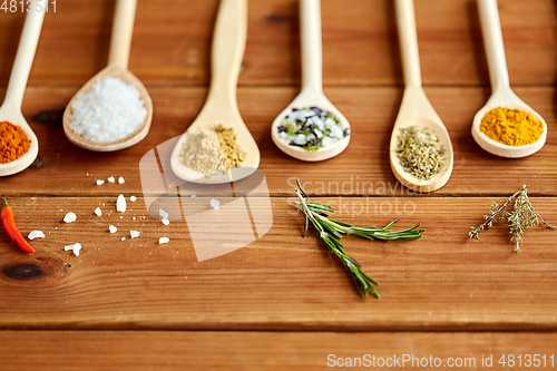 Image of spoons with spices and salt on wooden table