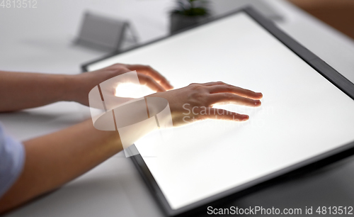 Image of hands on led light tablet at night office