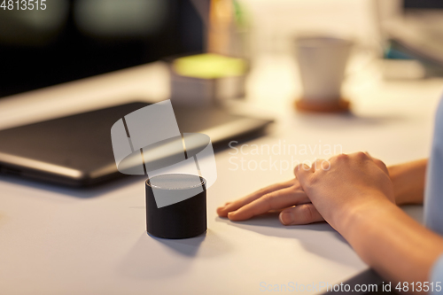 Image of close up of hand with smart speaker at office