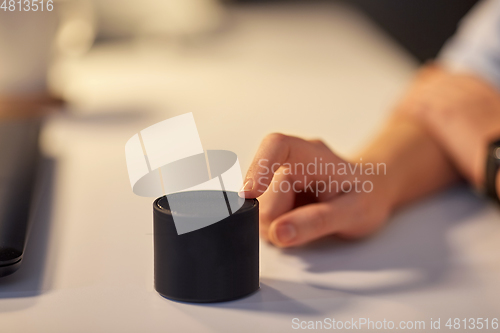 Image of close up of hand with smart speaker at office