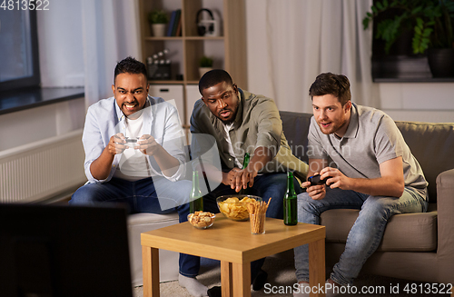 Image of happy friends playing video games at home at night