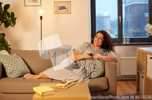 Image of happy woman drinking red wine at home in evening