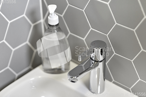 Image of close up of water tap with liquid soap on sink