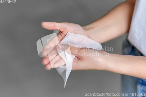 Image of woman cleaning hands with antiseptic wet wipe