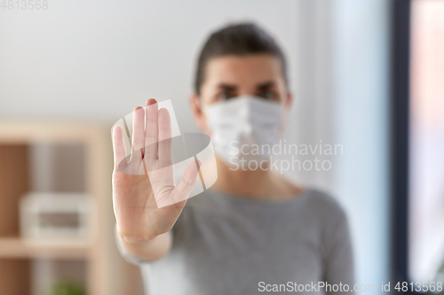 Image of woman in protective medical mask making stop sign