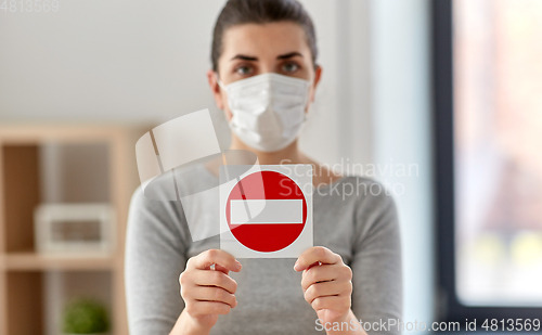 Image of woman in protective medical mask showing stop sign