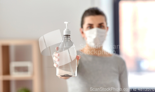 Image of close up of woman in mask holding hand sanitizer