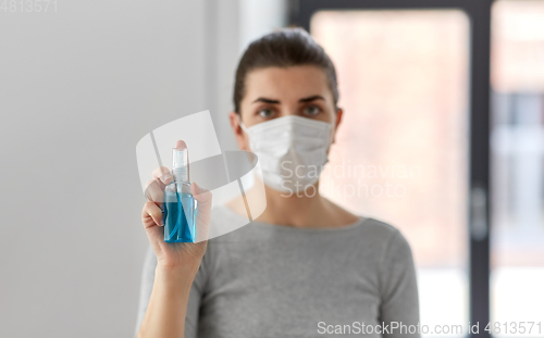 Image of close up of woman in mask holding hand sanitizer