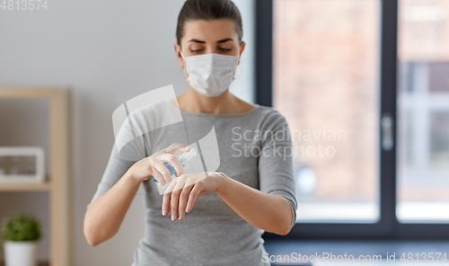 Image of close up of woman in mask spraying hand sanitizer