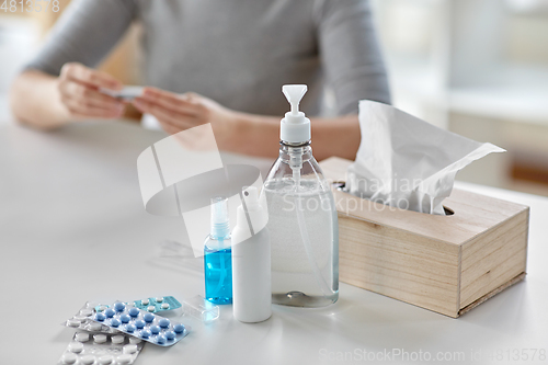 Image of medicines and sick woman with thermometer at home