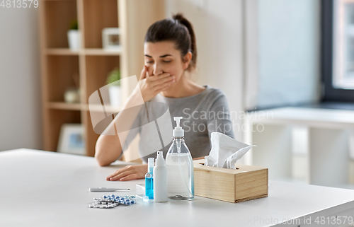 Image of medicines and sick woman coughing at home