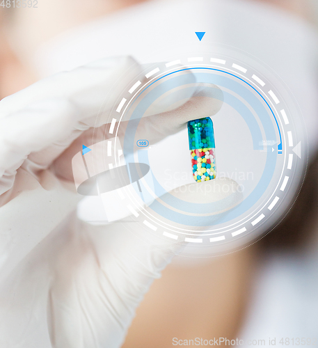 Image of close up of scientist holding pill in lab