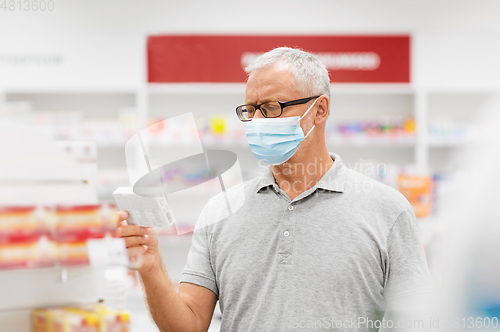 Image of senior man in medical mask with drug at pharmacy