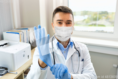 Image of doctor in medical mask wearing gloves at hospital