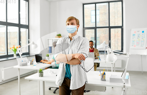 Image of man with glasses in medical mask at office