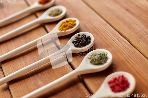Image of spoons with different spices on wooden table
