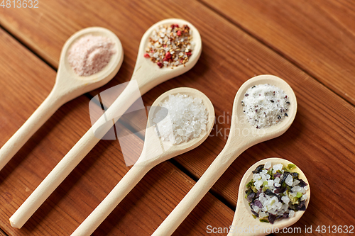 Image of spoons with salt and spices on wooden table