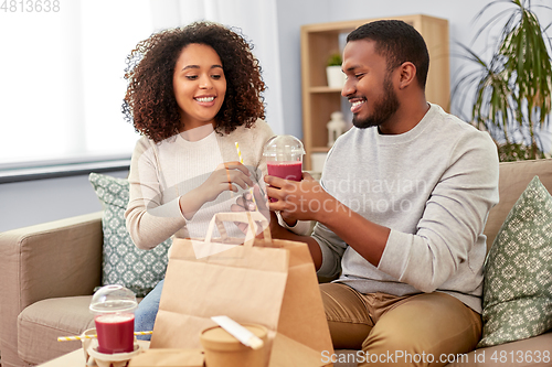 Image of happy couple with takeaway food and drinks at home