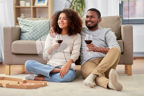 Image of happy couple with wine and takeaway pizza at home