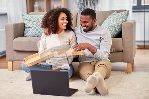 Image of happy african american couple eating pizza at home