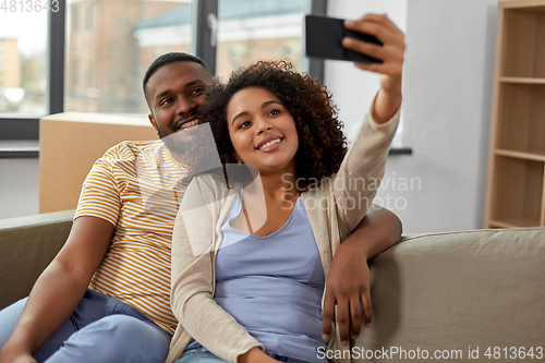 Image of happy couple moving to new home and taking selfie