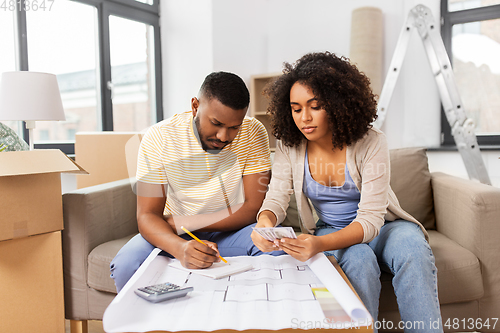 Image of couple with blueprint counting money at home