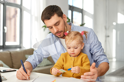 Image of working father with baby daughter at home office