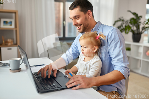 Image of working father with baby daughter at home office