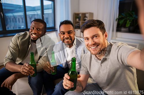 Image of happy male friends with beer taking selfie at home