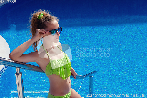 Image of teen girl relaxing near swimming pool