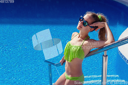 Image of teen girl relaxing near swimming pool