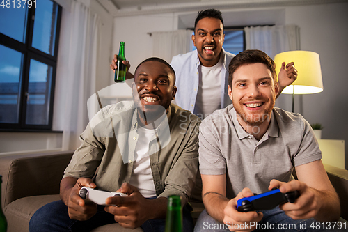 Image of happy friends playing video games at home at night