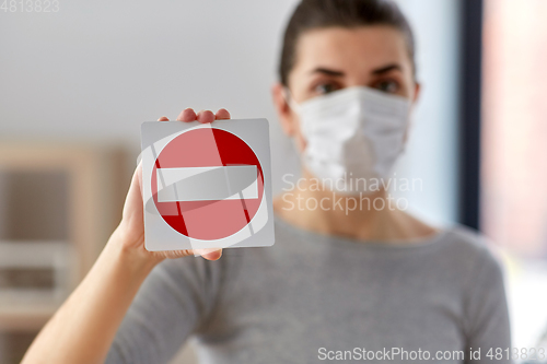 Image of woman in protective medical mask showing stop sign