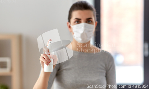 Image of close up of woman in mask holding hand sanitizer