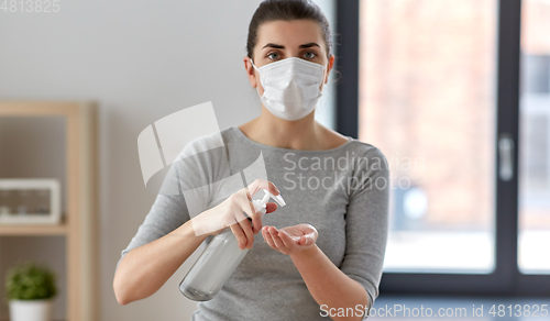 Image of close up of woman in mask applying hand sanitizer