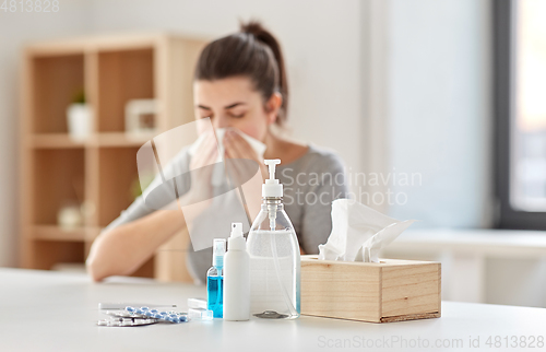 Image of medicines and sick woman blowing nose to wipe
