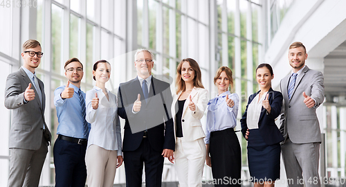 Image of business people showing thumbs up at office