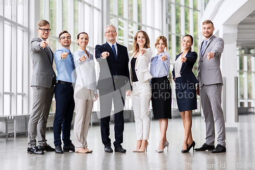 Image of business people pointing to camera at office