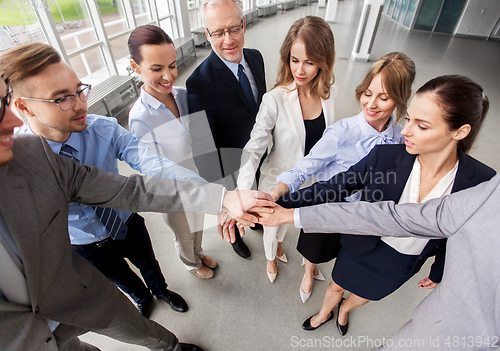 Image of happy business people stacking hands at office