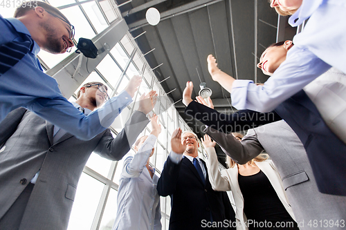 Image of business people making high five at office
