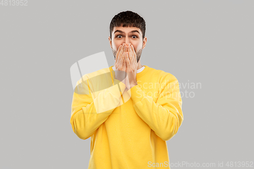 Image of shocked young man covering his mouth with hands