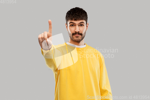 Image of young man in yellow sweatshirt showing one finger