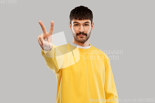 Image of young man showing peace over grey background