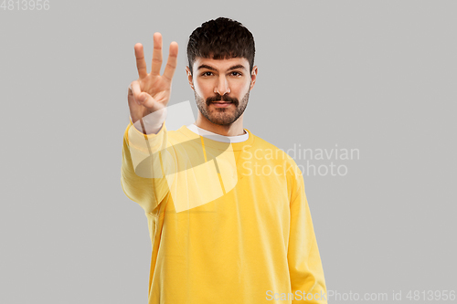 Image of man in yellow sweatshirt showing three fingers