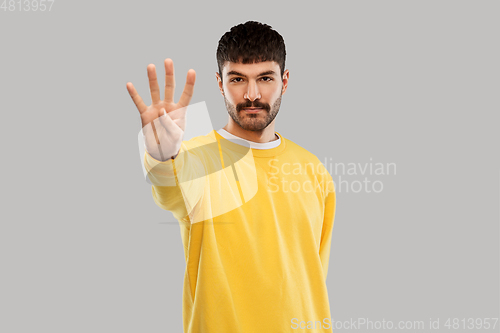 Image of man in yellow sweatshirt showing four fingers