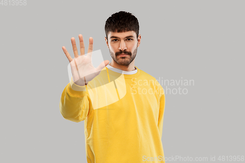 Image of serious young man showing stop gesture