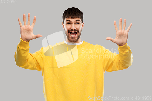 Image of smiling young man showing his hand or ten fingers