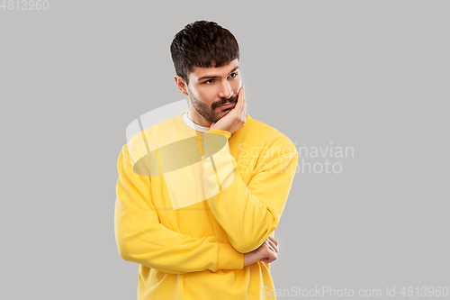 Image of sad young man in yellow sweatshirt thinking