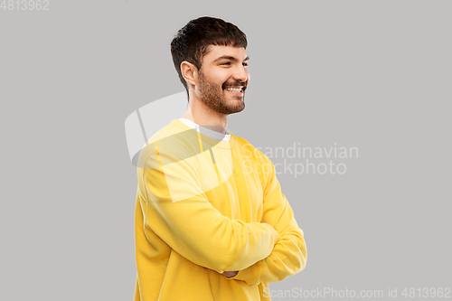 Image of young man in yellow sweatshirt with crossed arms