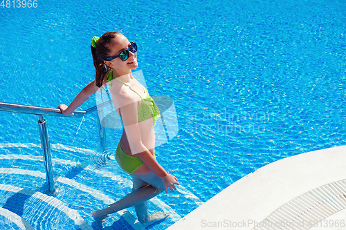 Image of teen girl relaxing near swimming pool